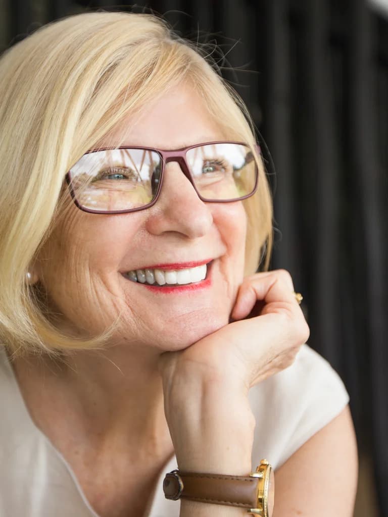 Smiling senior woman resting her chin on her hand, free of dental pain